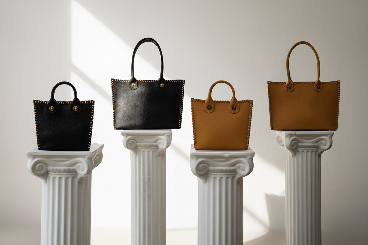 Four handbags in black, brown, and beige on classical columns against a white background